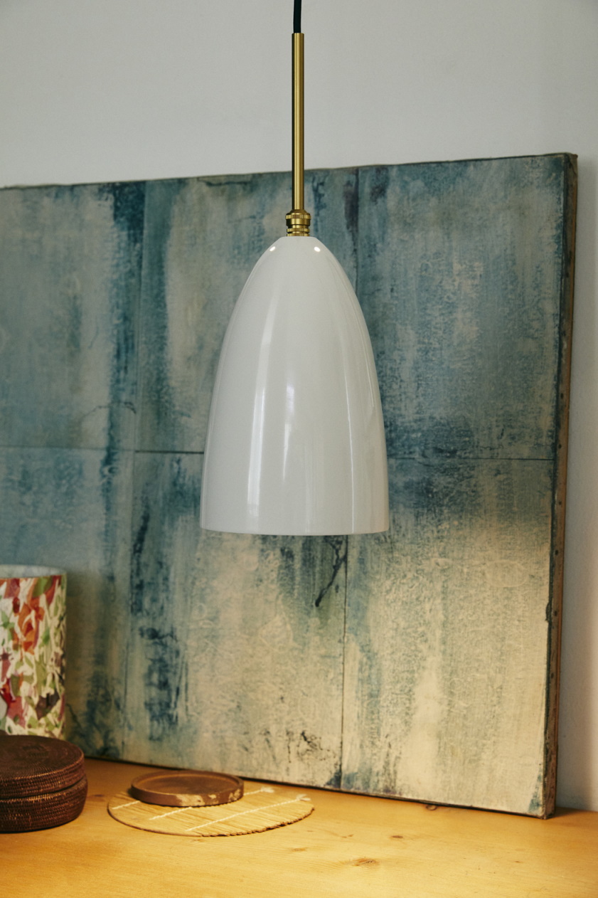 Nahaufnahme der Gräshoppa Pendelleuchte von Gubi, alabasterweiß glänzend mit goldenem Detail, moderne Innenbeleuchtung.