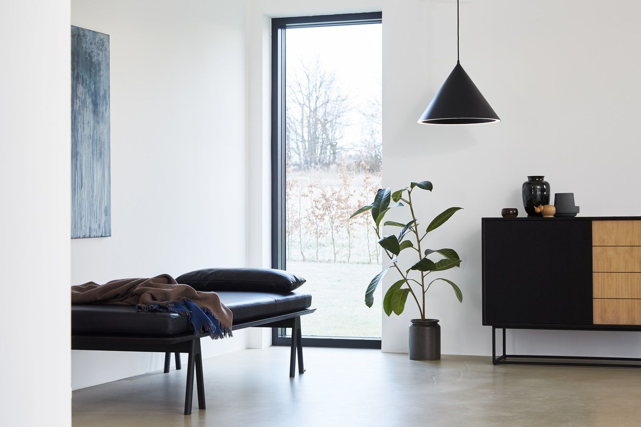 Schwarze Annular Pendelleuchte von Woud über einem modernen Wohnzimmer mit minimalistischem Design. Hängelampe für stilvolle Beleuchtung.