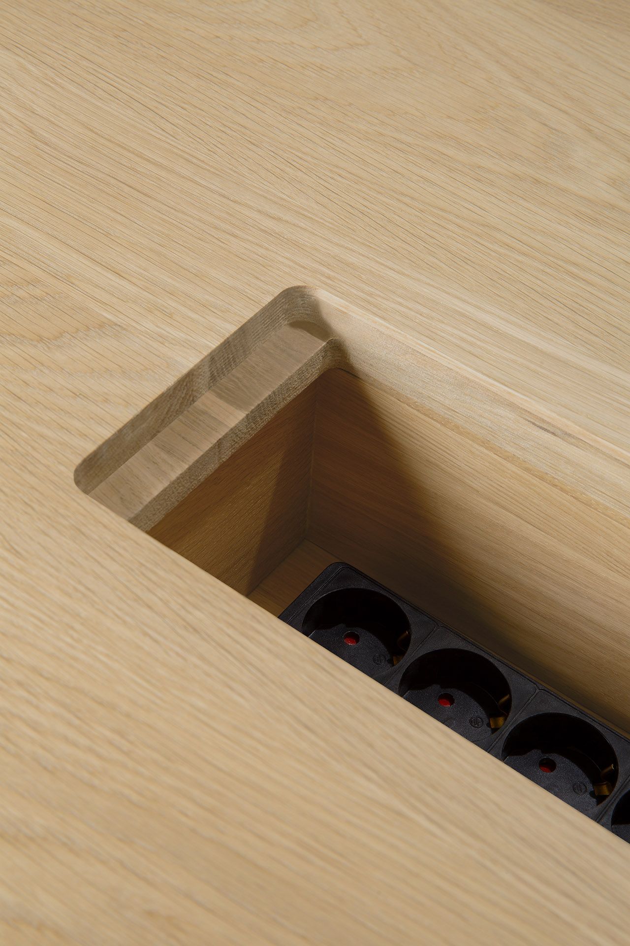 Detailaufnahme: Geometric Meetingtisch Eiche lackiert mit integrierter Kabelbox und Mehrfachsteckdose.