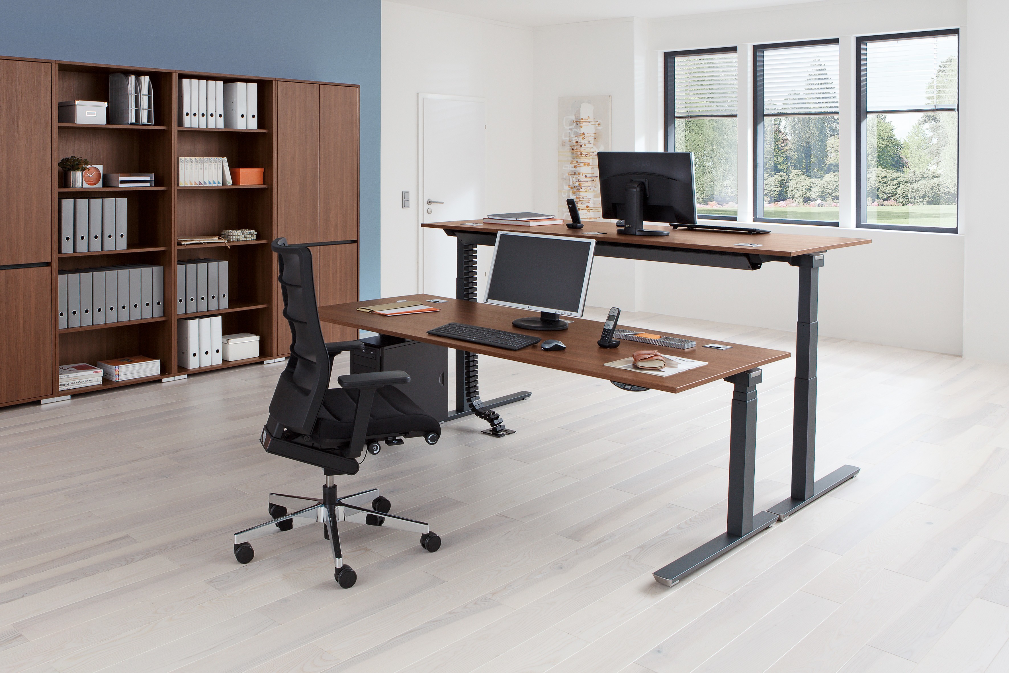 Büro mit Palmberg Schreibtisch, höhenverstellbar, in Holzoptik mit zwei Ebenen und Büromöbeln.