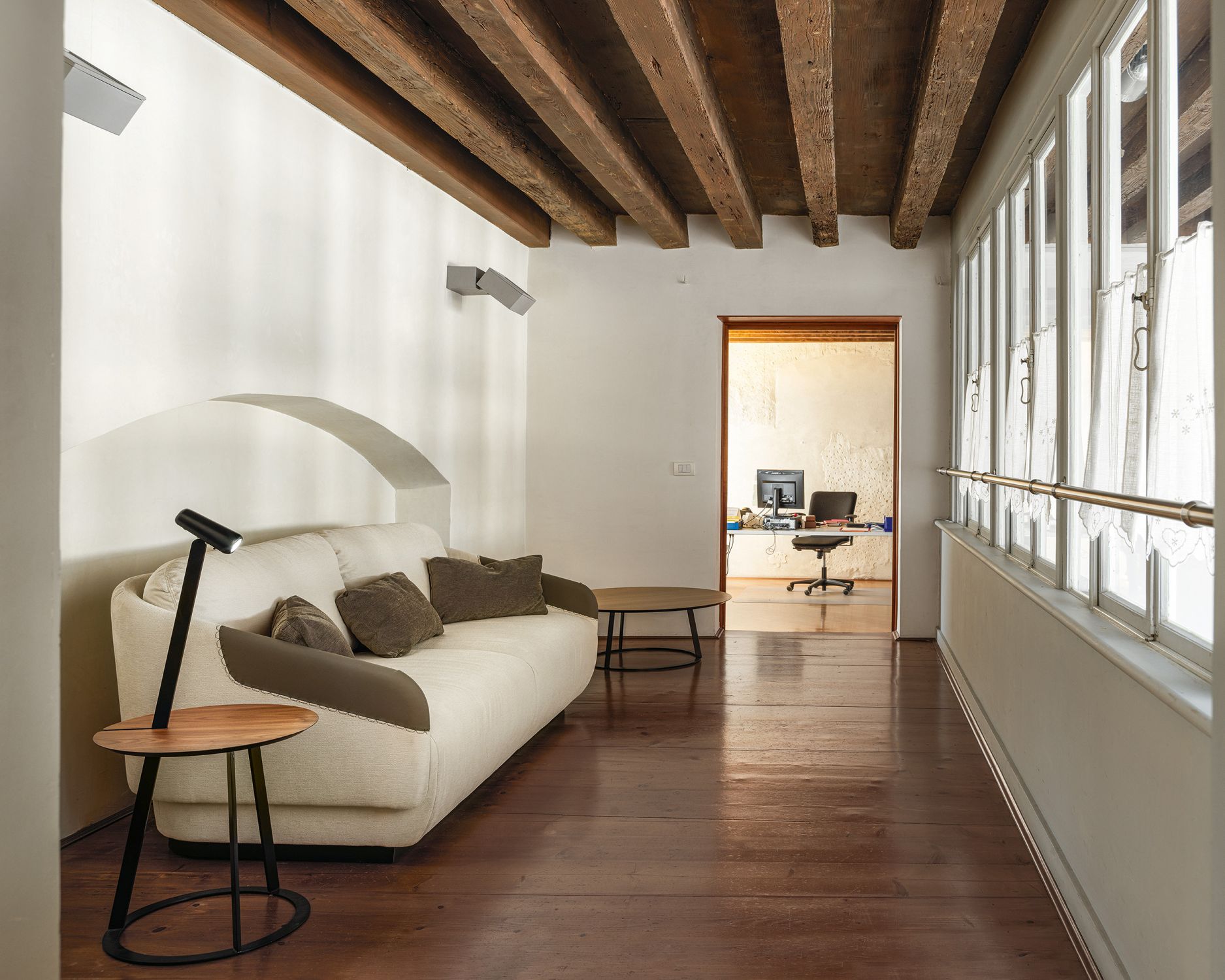 Albino Torcia Beistelltisch in Walnuss und Schwarz neben Sofa im Wohnzimmer.