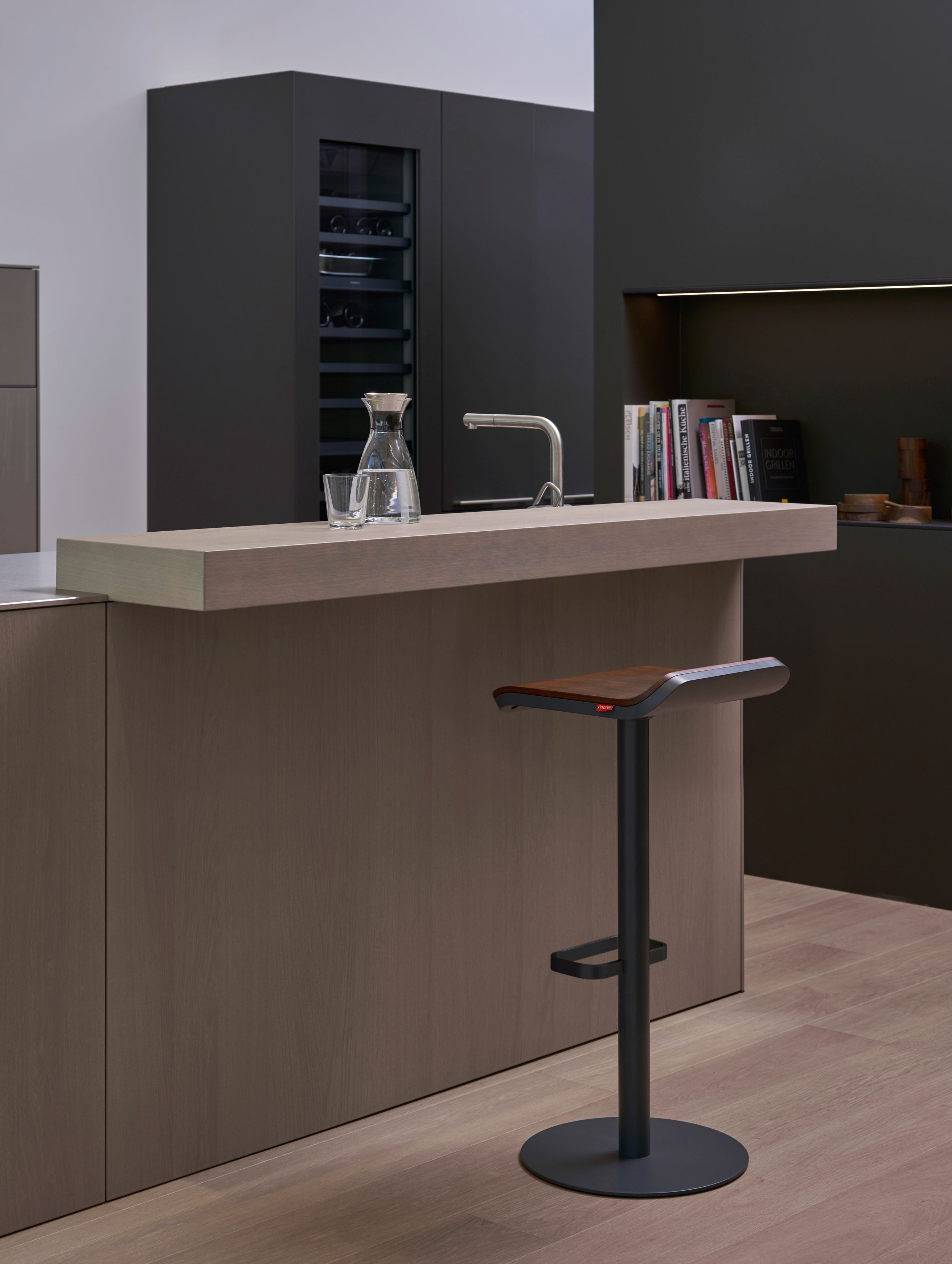 Moderner Barhocker von Moree, Modell ED, in Anthrazit und Walnuss vor Kücheninsel.