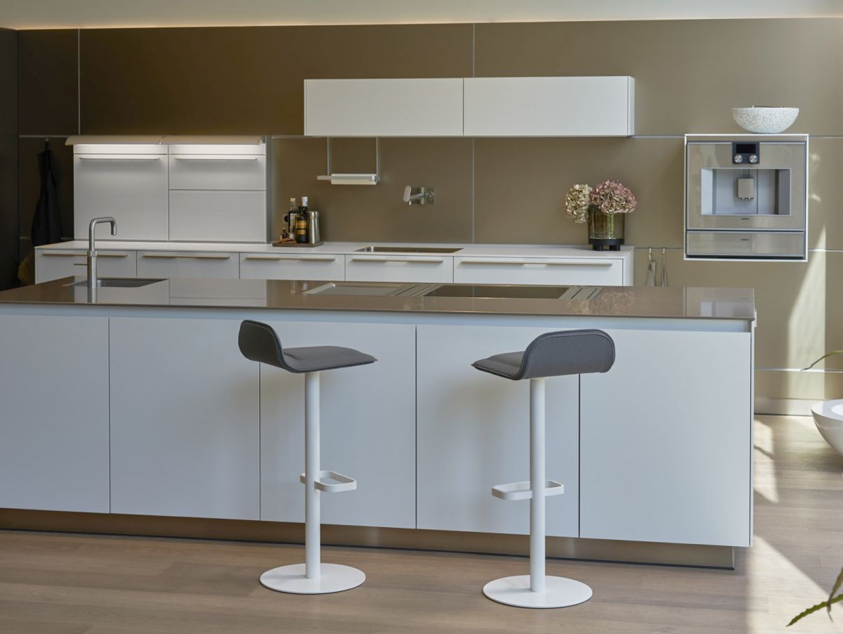 Dave Barhocker von Moree, weiße Ausführung mit anthrazitfarbenem Sitzpolster vor moderner Kücheninsel.