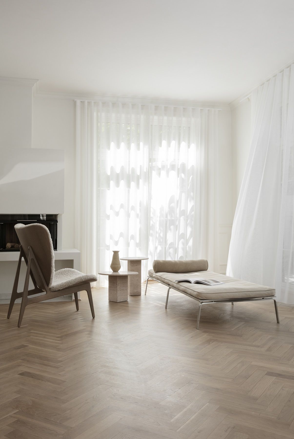 Wohnzimmer mit NORR11 Soho Couchtisch aus Travertin, Sessel und Liege in hellem, minimalistischem Design.