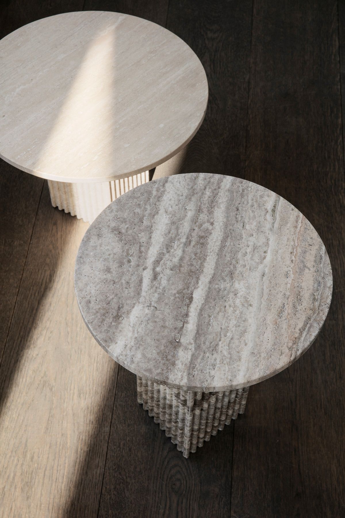 Zwei runde Soho Coffee Table Couchtische von NORR11 aus Travertin auf dunklem Holzboden.