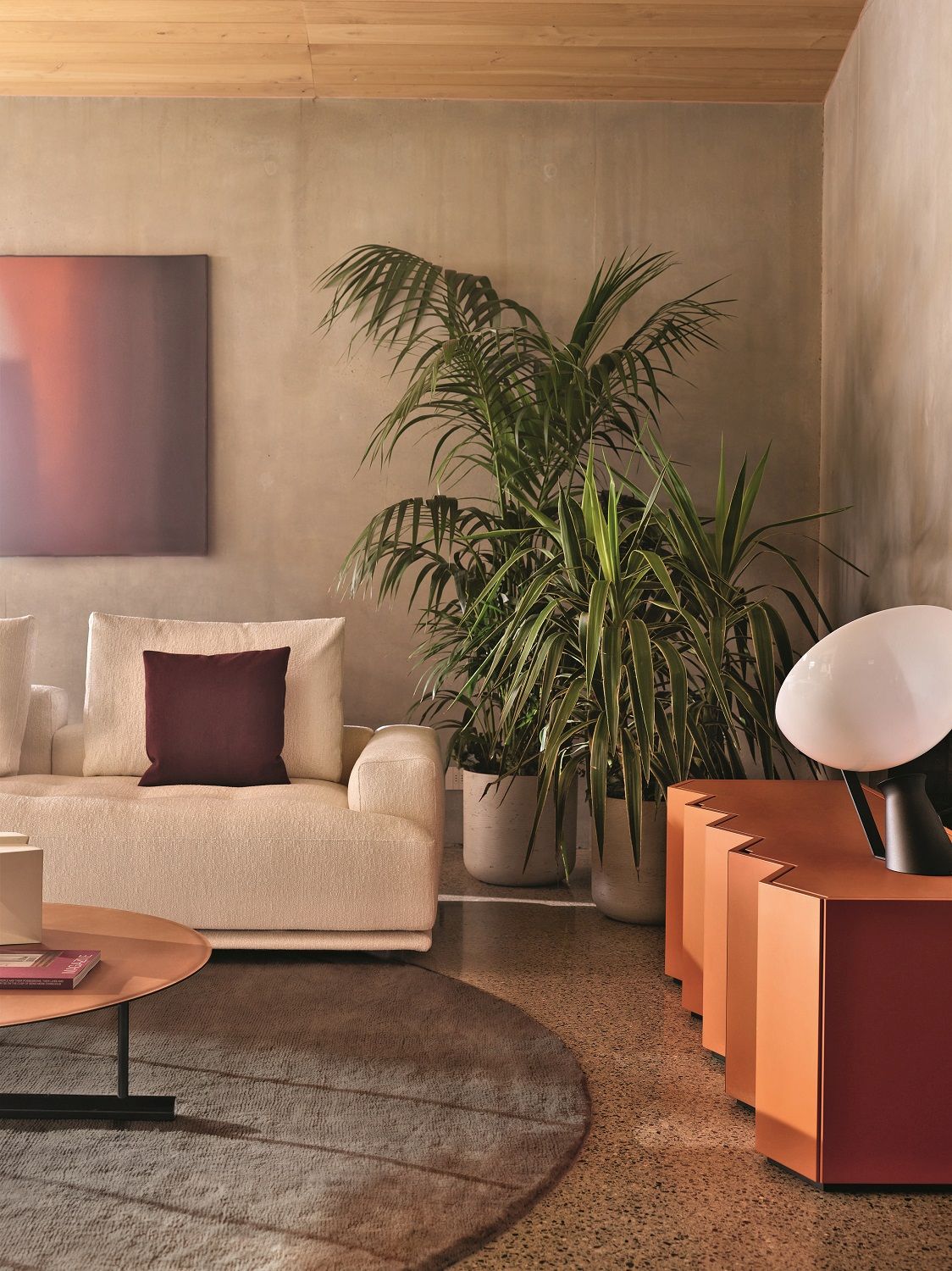 Wohnzimmer-Szene mit Zanotta Sideboard in Orange, Sofa, runder Teppich und Zimmerpflanzen für ein modernes Ambiente.