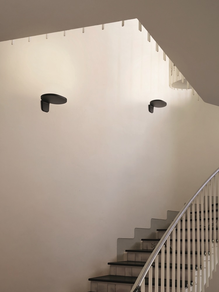 Zwei schwarze Oplight W1 Wandleuchten von Flos an einer Treppenhauswand, modernes Design.