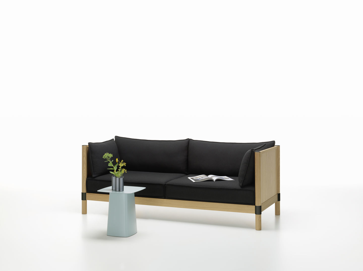 Blauer Metal Side Table Beistelltisch von Vitra neben einem Sofa mit Blumen.