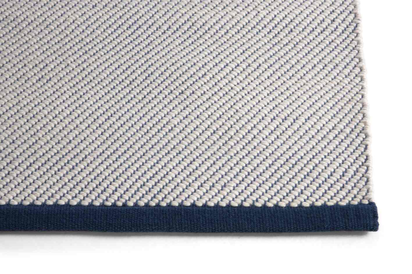 Detailansicht des Bias Rug Tint Teppichs in Ocean Tint: Hochwertiger Teppich mit blauem Rand.