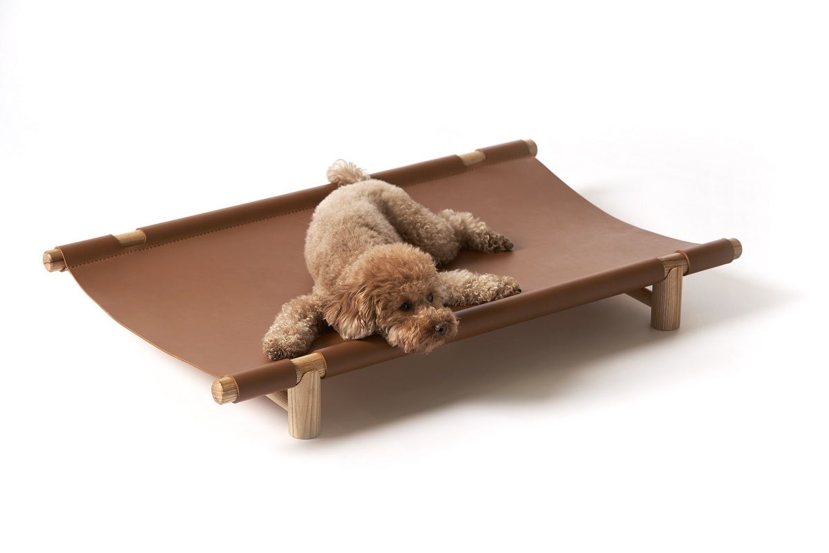 Brauner Pudel entspannt auf dem Berberé Hundebett von Opinion Ciatti, einem tragbaren Hundebett.