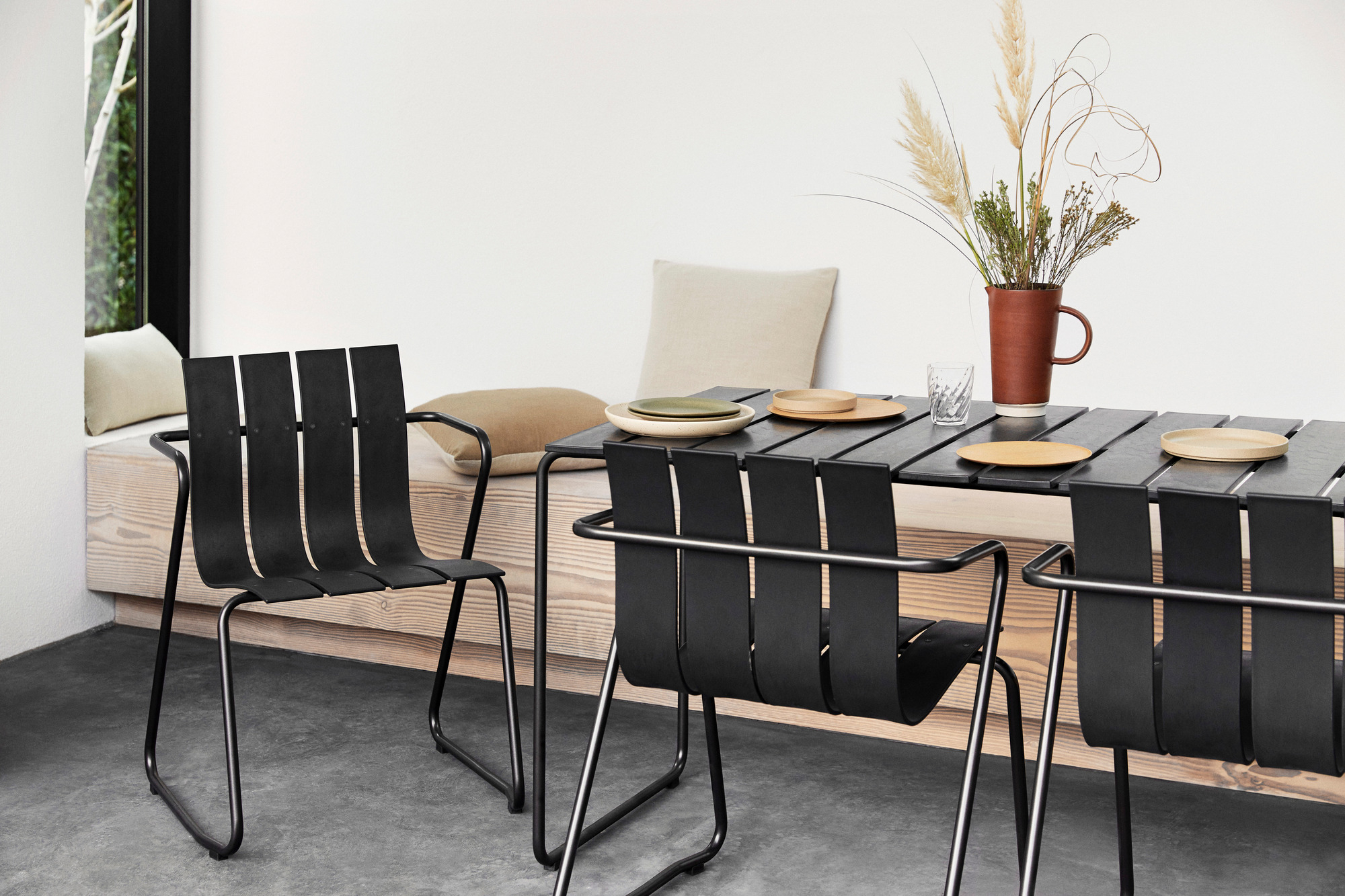 Schwarzer Ocean Tisch mit vier Stühlen für den Außenbereich, modernes Design mit Tellern und Dekoration.