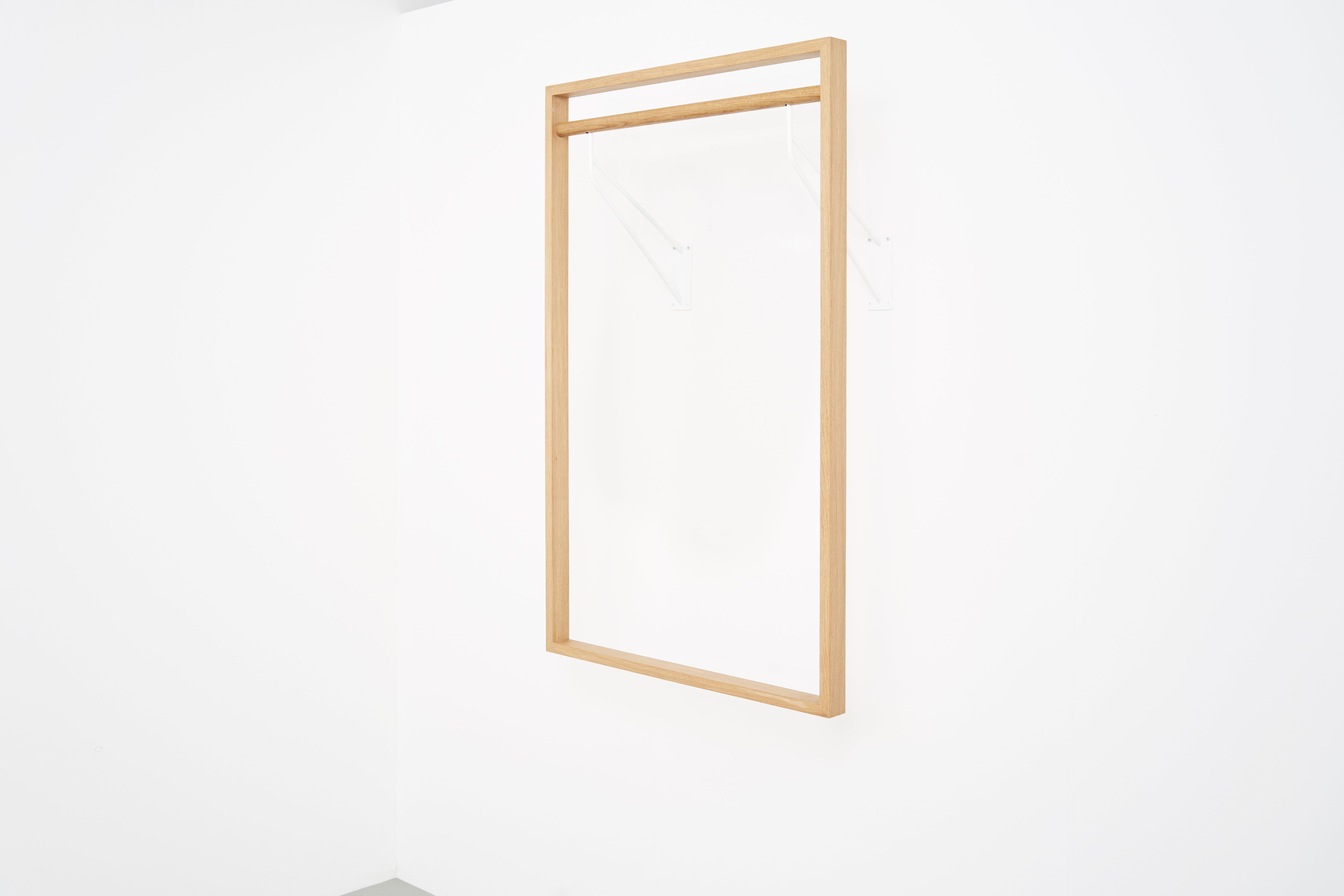 gardero-b 2 Wandgarderobe: Helle Holzgarderobe mit weißen Halterungen an einer weißen Wand.