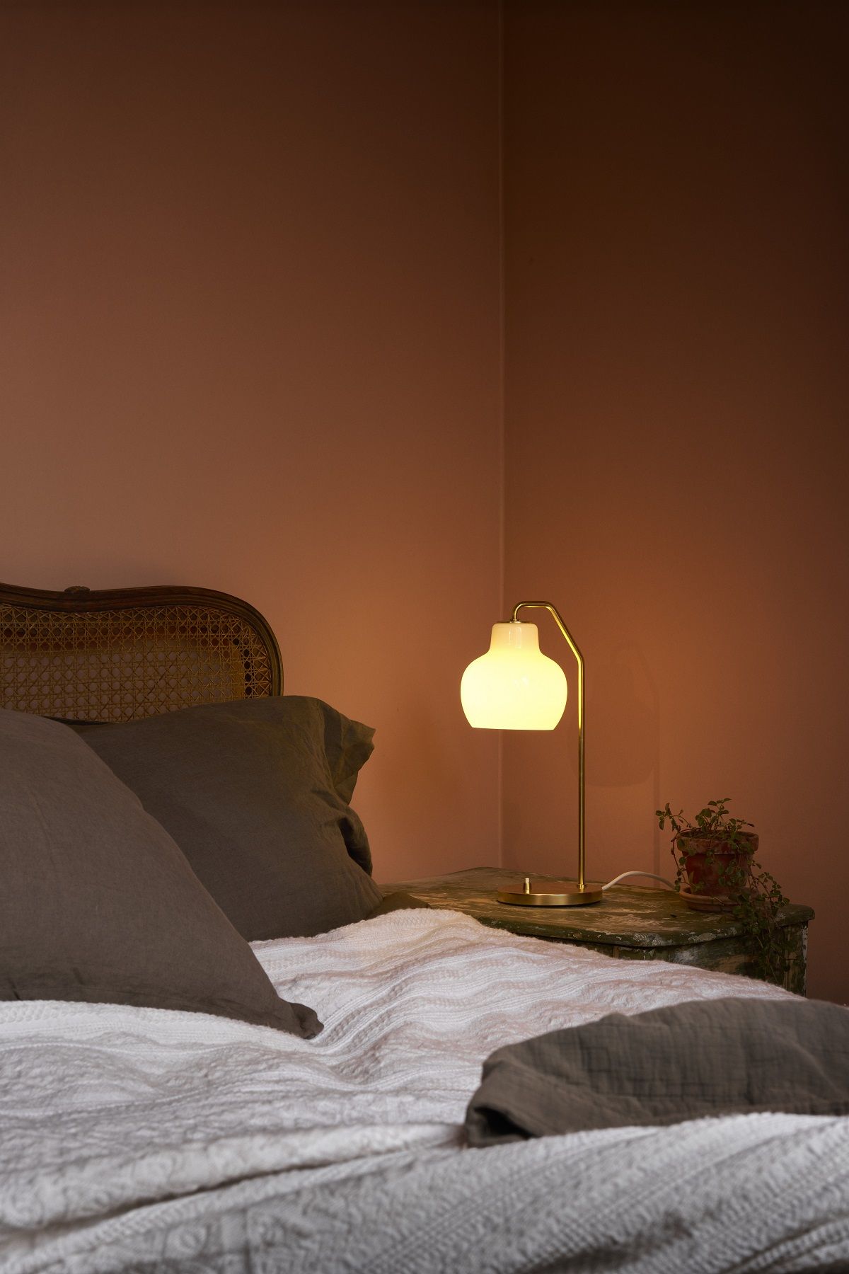 VL Ring Crown Tischleuchte von Louis Poulsen auf Nachttisch neben Bett mit Kissen.