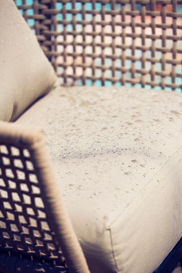 Detailaufnahme: Taupefarbener Suka Lounge Sessel von Jan Kurtz mit Wassertropfen auf dem Outdoor-Kissen.