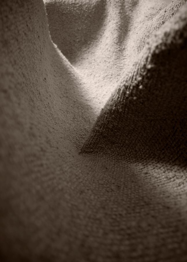 Detailaufnahme des hellen Bouclé-Stoffbezugs vom Beetle Chair Stuhl von Gubi. Textur und Haptik.