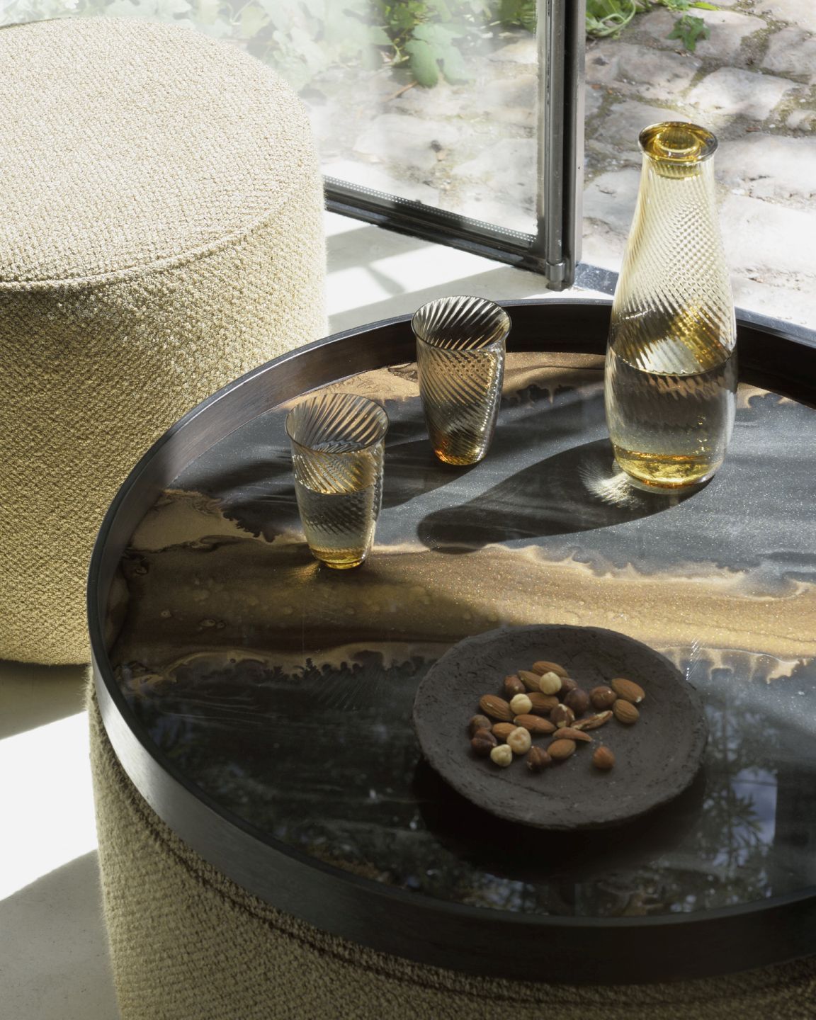 Barrow Sitzhocker von Ethnicraft in Ingwer: Detailaufnahme mit Tisch, Gläsern und Nüssen.