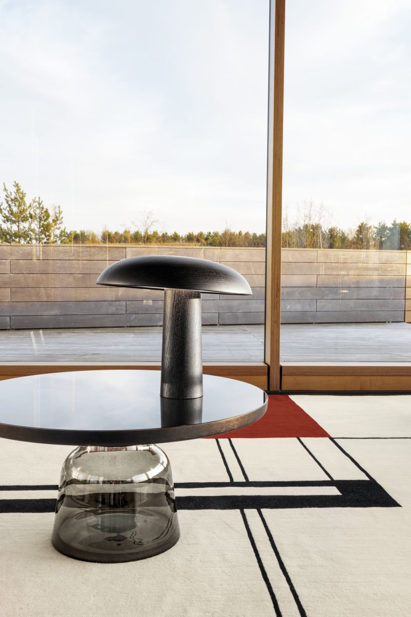 Detailaufnahme des ClassiCon Wendingen Teppichs 300x250cm mit geometrischem Muster in Schwarz, Weiß und Rot unter einem Beistelltisch.