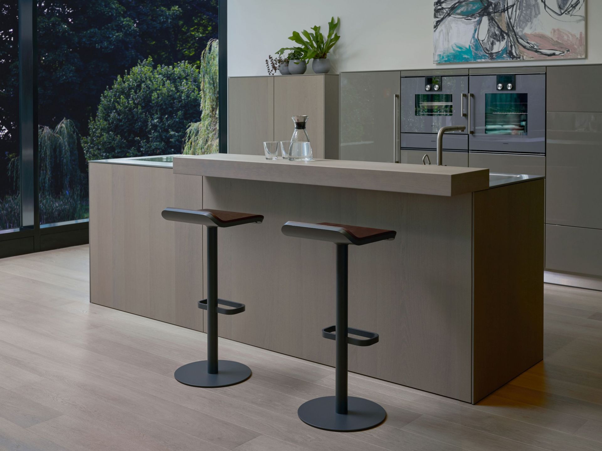 Zwei anthrazitfarbene Moree Barhocker mit Walnuss-Sitzfläche an einer Kücheninsel. Moderne Barstühle für die Küche.