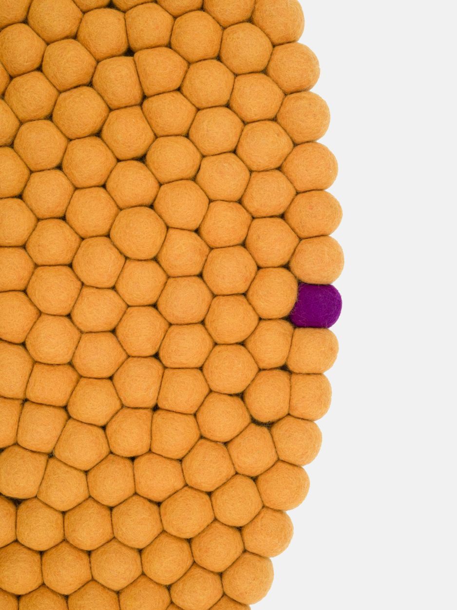 Detailaufnahme des ockergelben Big One Filzteppichs (Ø 200 cm) von myfelt, bestehend aus vielen Filzkugeln.
