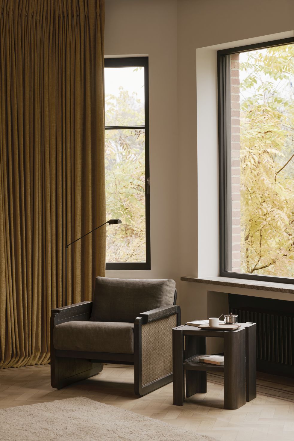 Ethnicraft Panel Beistelltisch aus dunklem Holz neben Sessel in modernem Wohnzimmer mit Fenster.