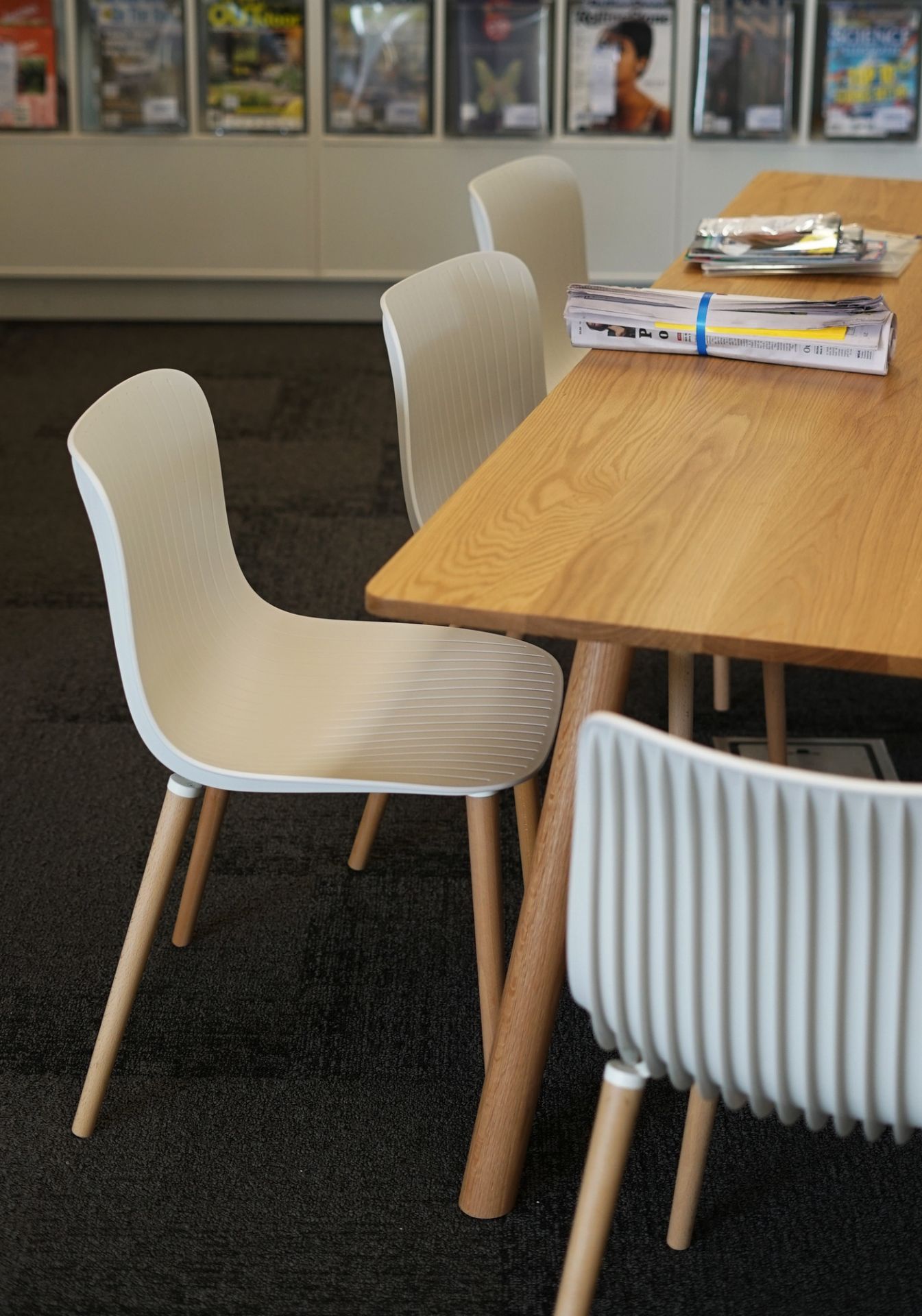 Ansicht eines modernen Stuhls mit Holzbeinen, ähnlich dem Dragonfly Stuhl, im Büro.