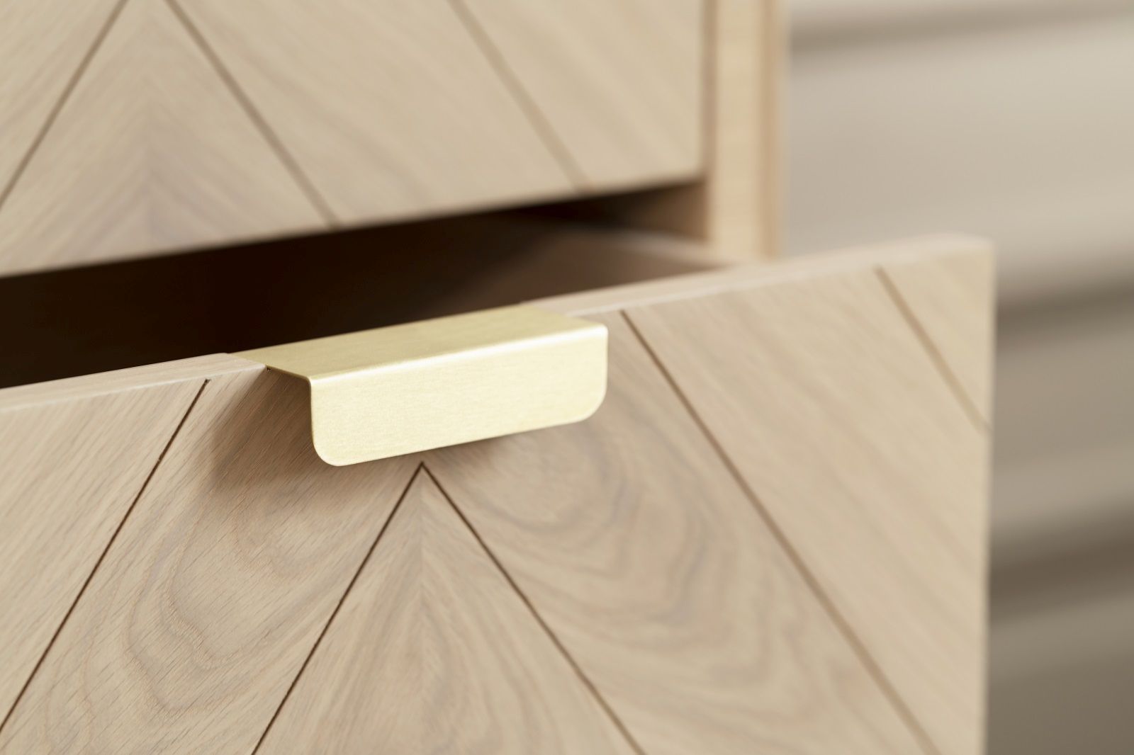Detailaufnahme: Geöffnete Schublade der Hartô Marius Kommode aus hellem Holz mit Fischgrätenmuster und goldenem Griff.