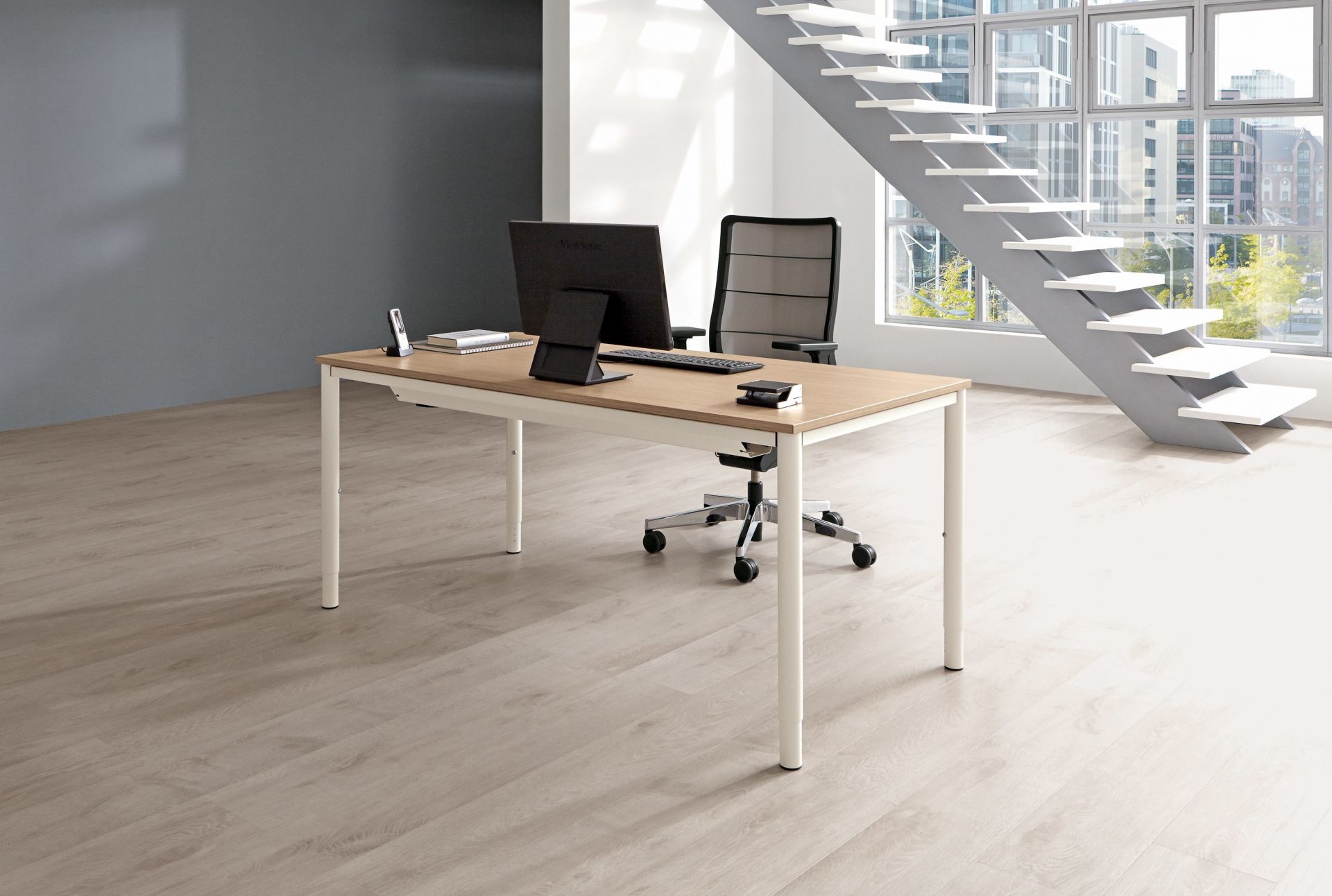 Moderner Palmberg Schreibtisch Sinac, höhenverstellbar, mit Bürostuhl, Monitor und Büromaterial in hellem Büro.