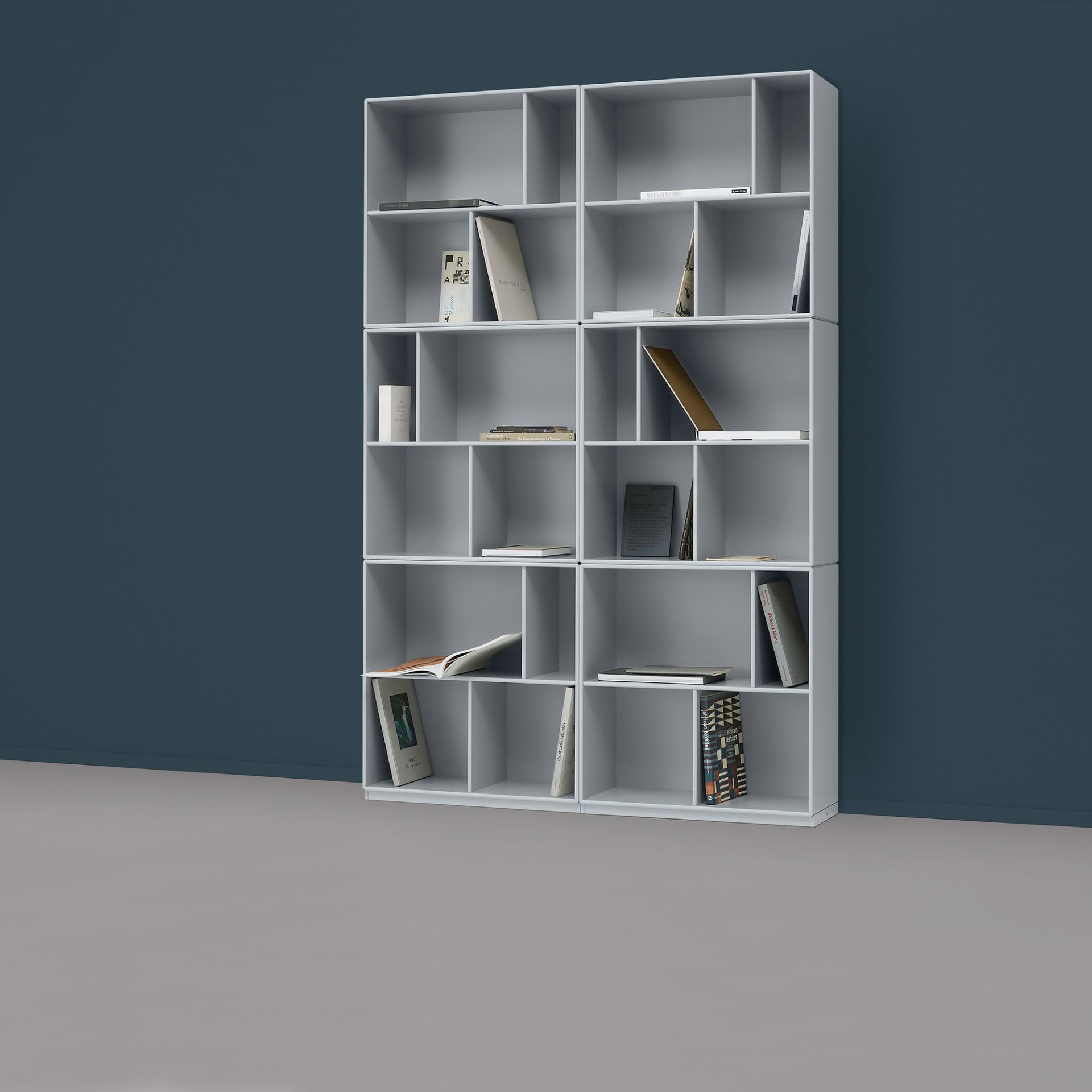 Graues Montana Bücherregal mit Fächern, gefüllt mit Büchern. Modernes Bücherregal für Wohnzimmer und Büro.