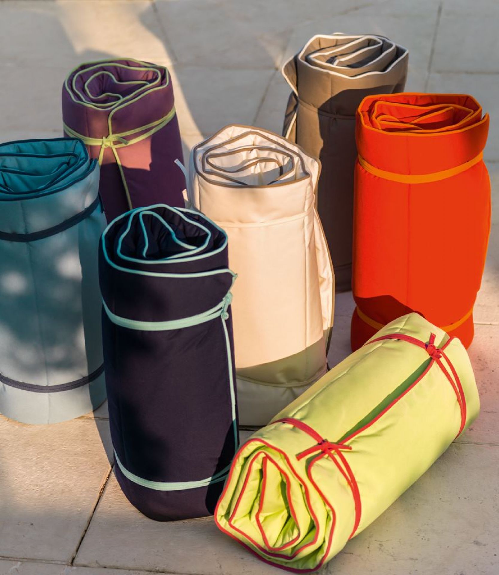 Gerollte Weishäupl Sonnenliegen in verschiedenen Farben, ideal für Balkon und Garten.