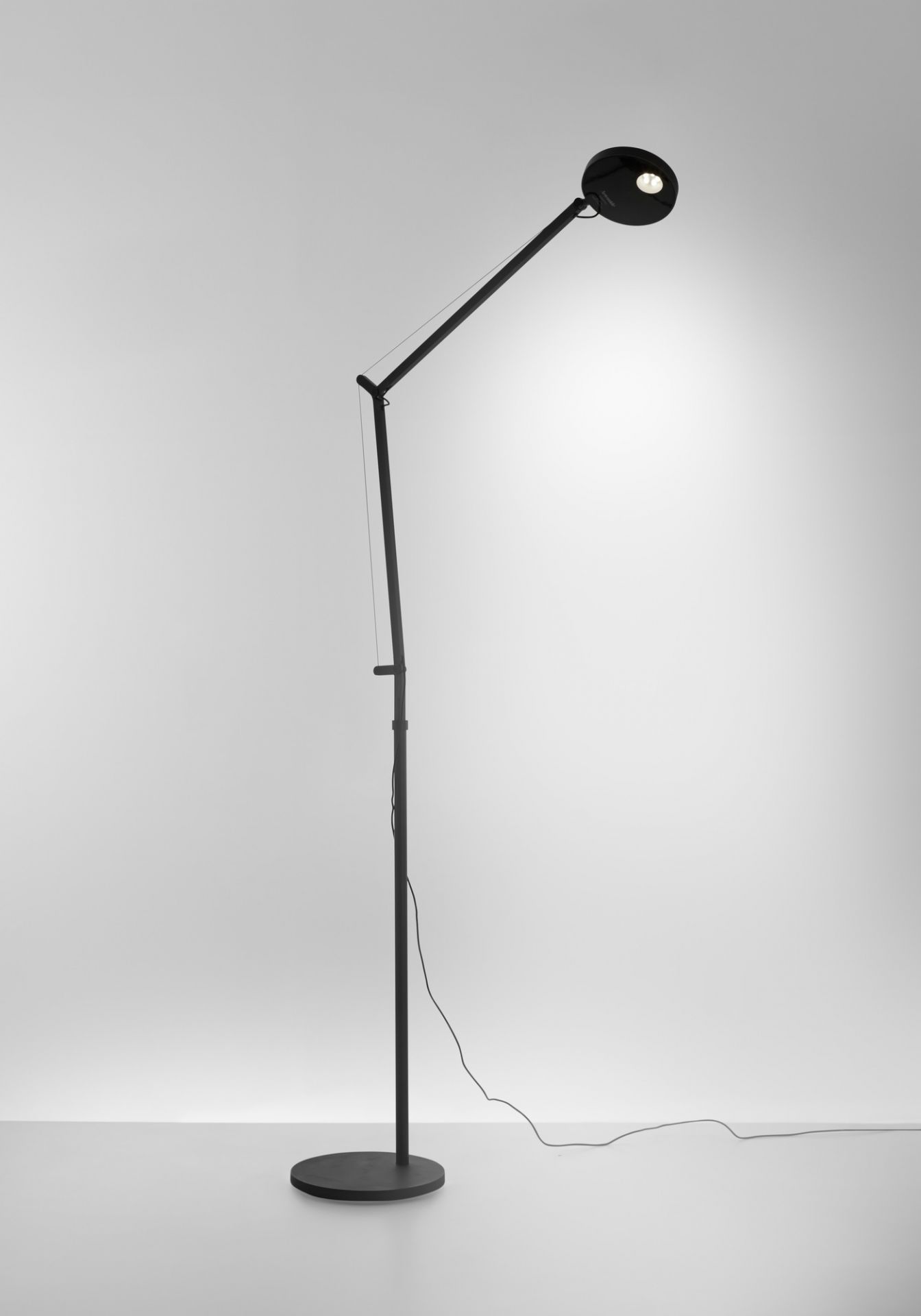 Schwarze Demetra Stehleuchte von Artemide mit rundem Leuchtenkopf und verstellbarem Arm.