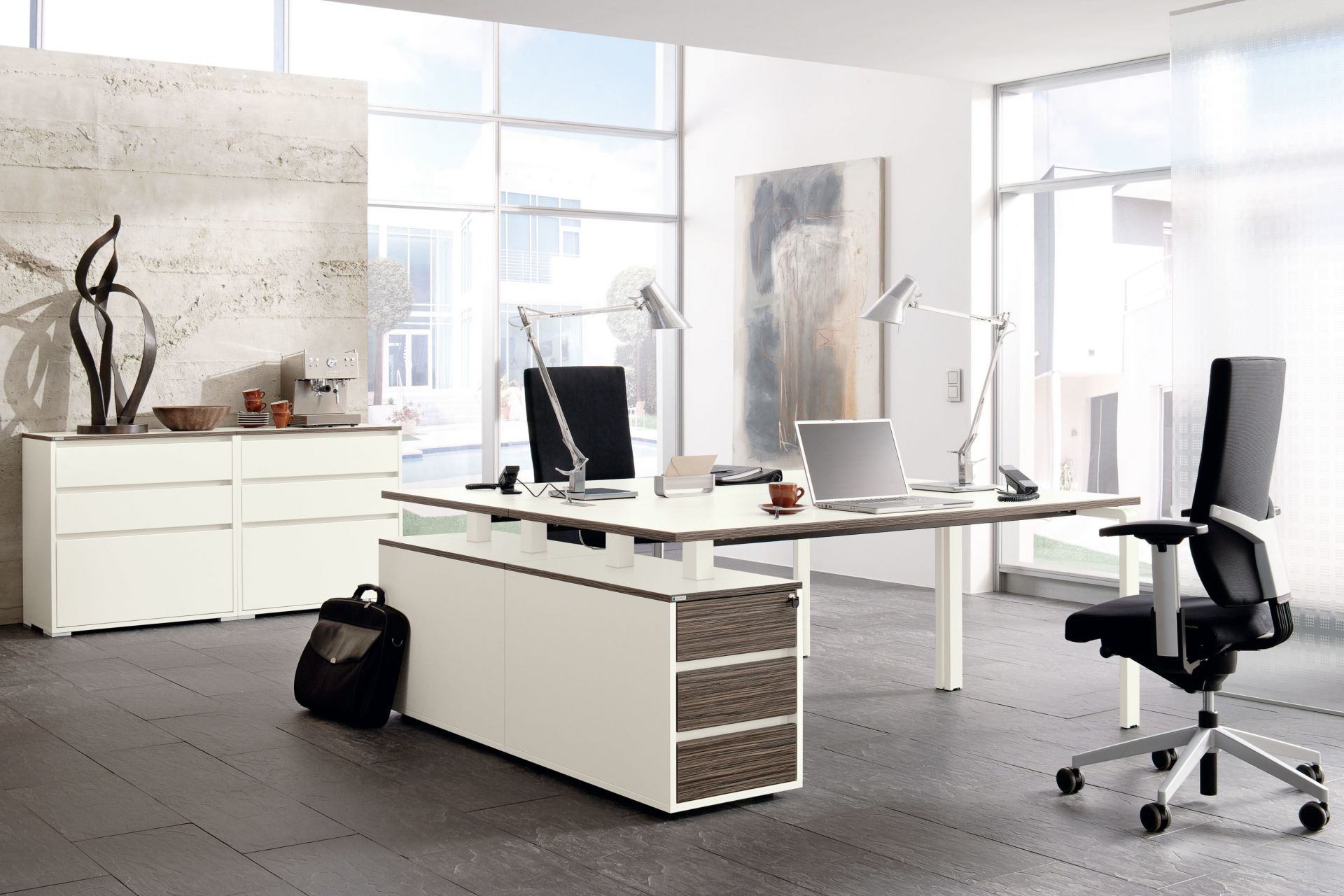 Moderner Büroraum mit Palmberg Pensum Besprechungstisch in Bootsform, Schreibtischlampe und Bürostuhl.