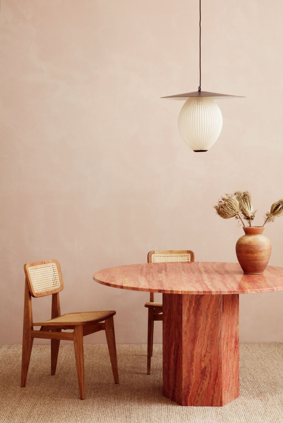 Runder Esstisch aus rotem Travertin, ähnlich dem Epic Table von Gubi, mit Holzstühlen.