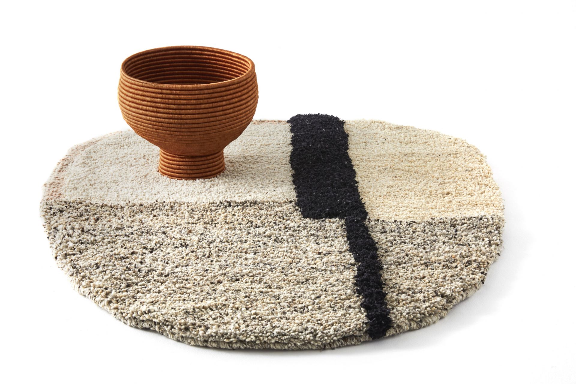 Ames Nudo Teppich small, beige mit schwarzem Muster und braunem Korb.