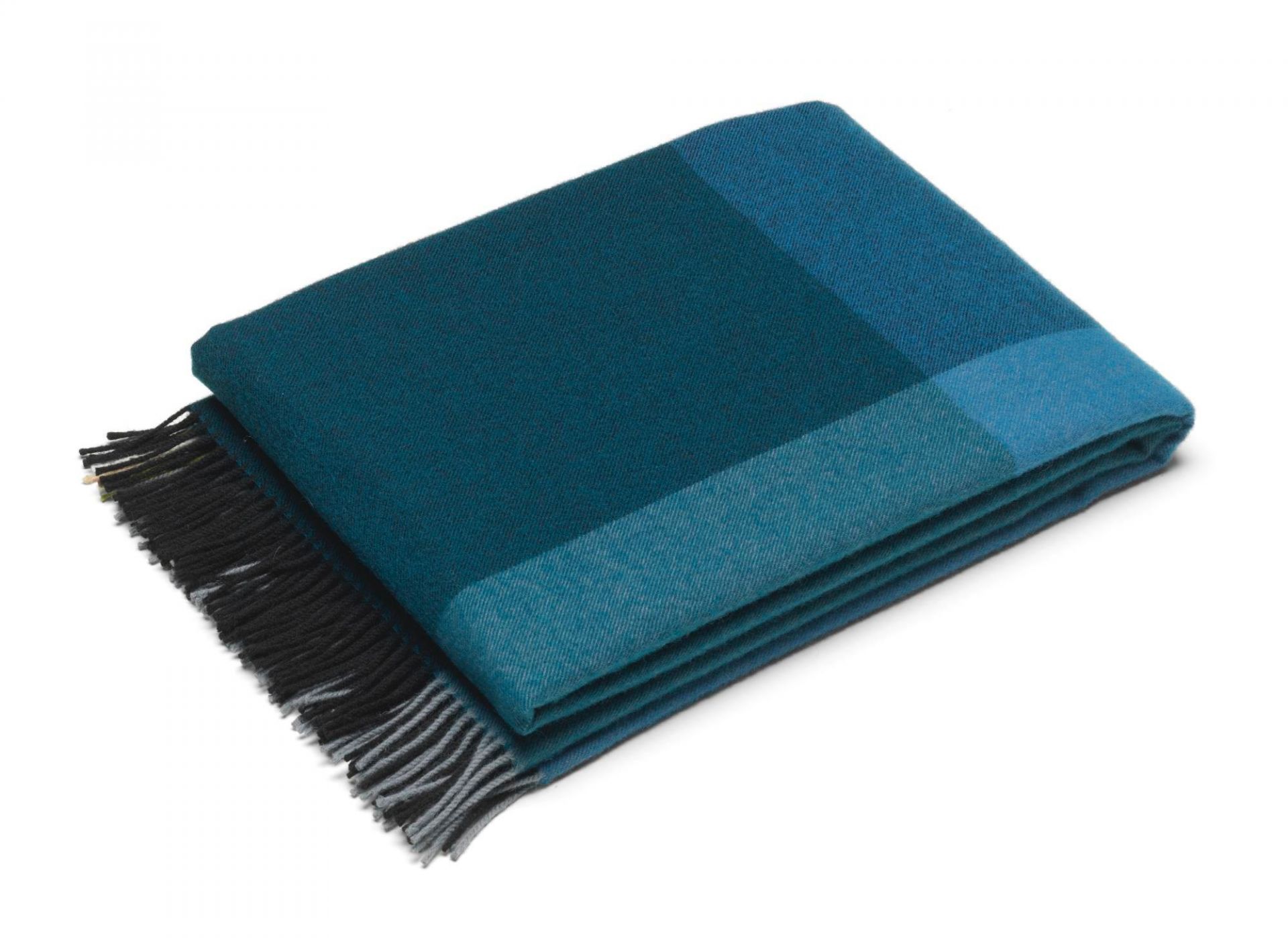 Gefaltete, blau-schwarze Wolldecke mit Fransen. Vitra Colour Block Blanket für gemütliche Stunden.